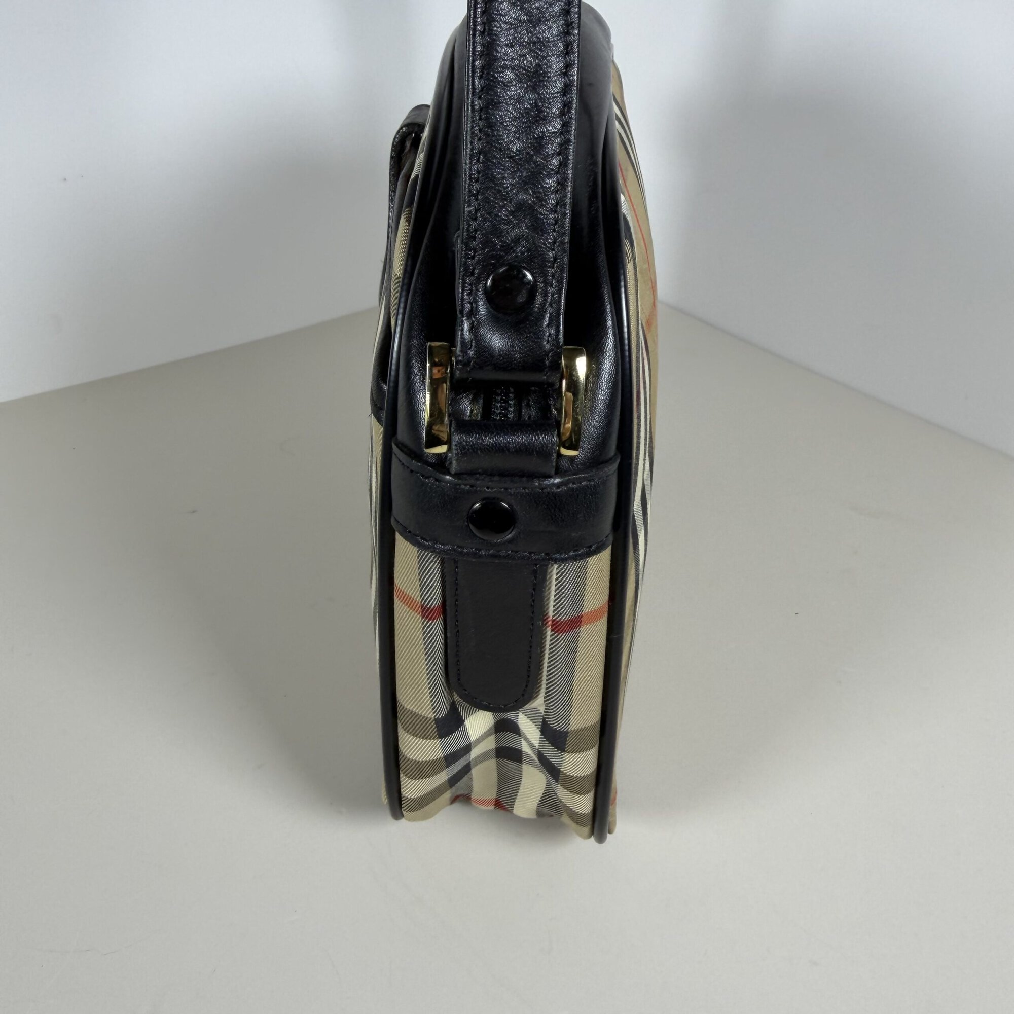 Opposite side profile of Burberrys crossbody bag showing side gusset and leather trim.