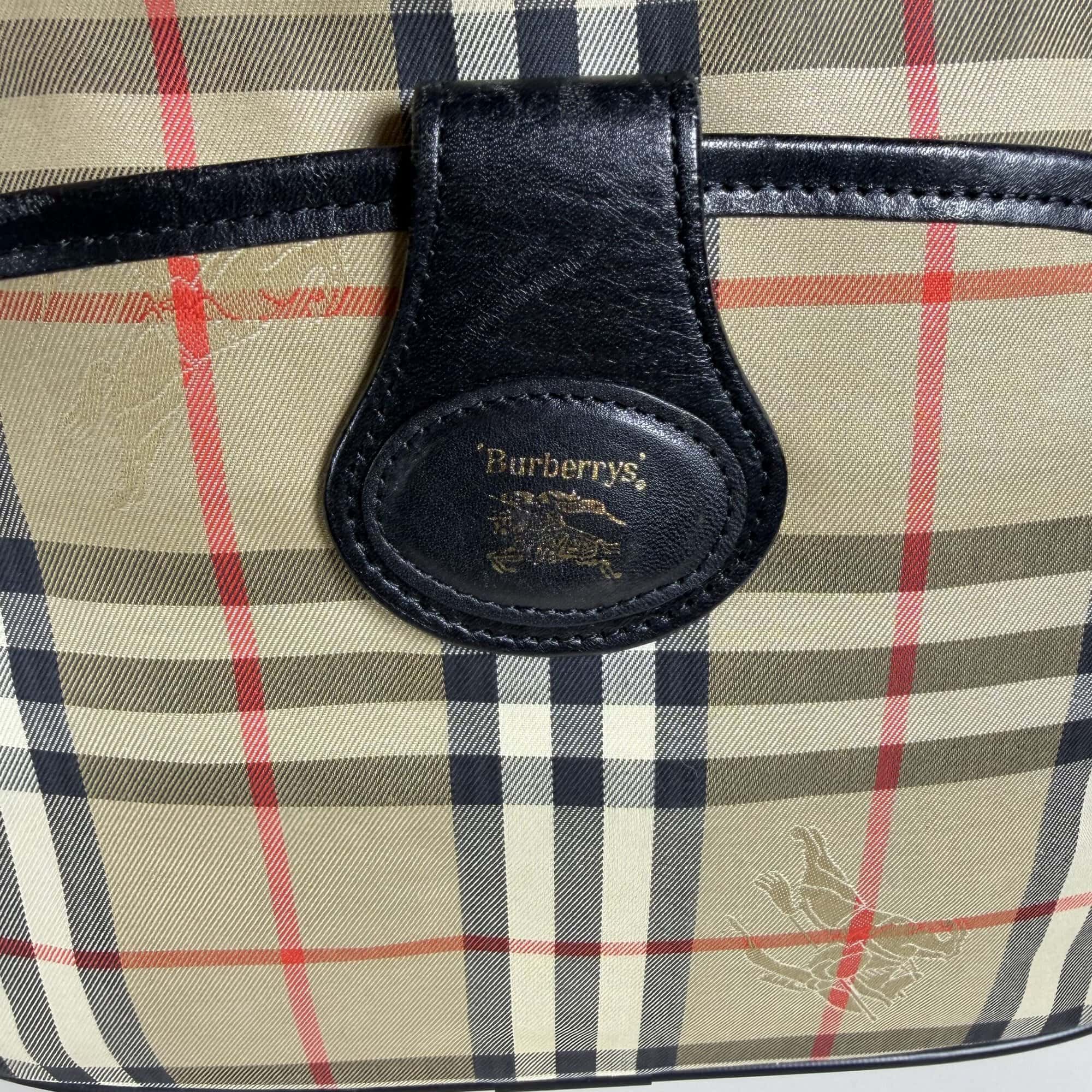 Close-up of black leather tab with gold-foil stamped Burberrys crest and equestrian knight logo.