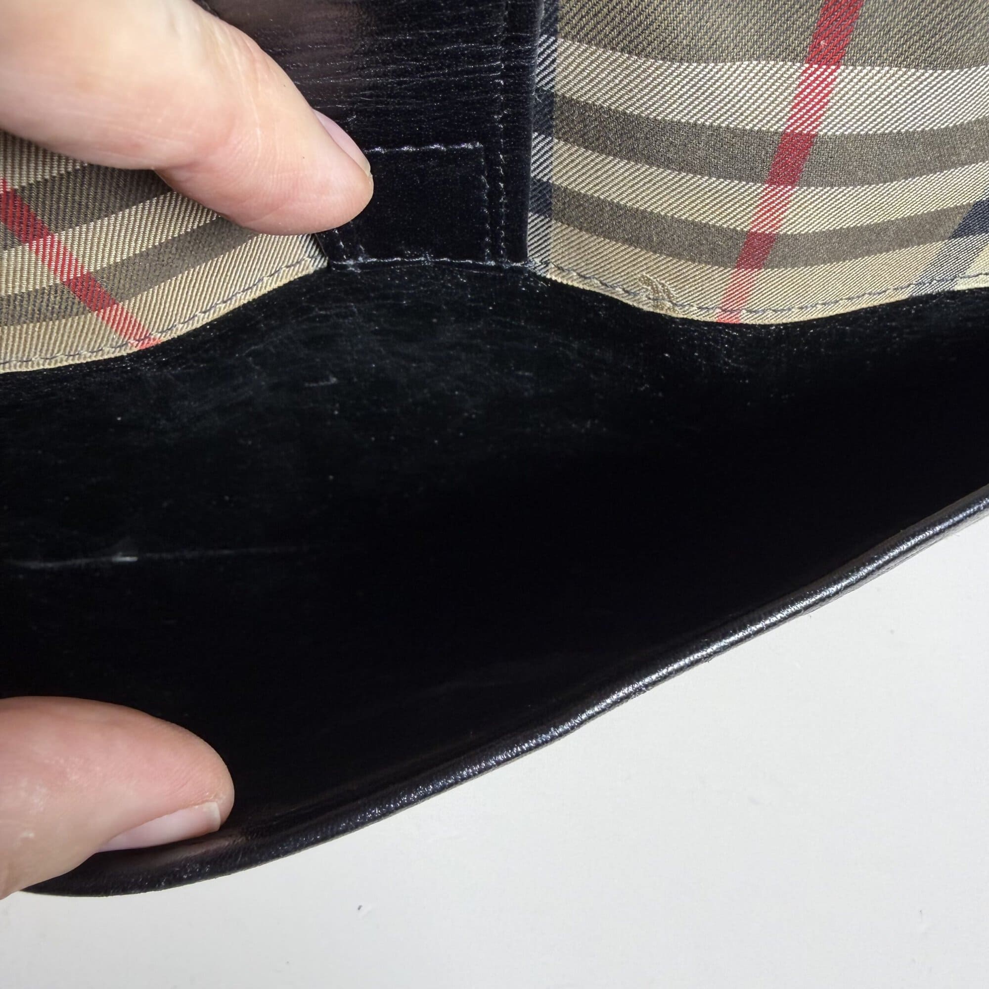 Interior of front exterior slip pocket showing black lining under leather tab.