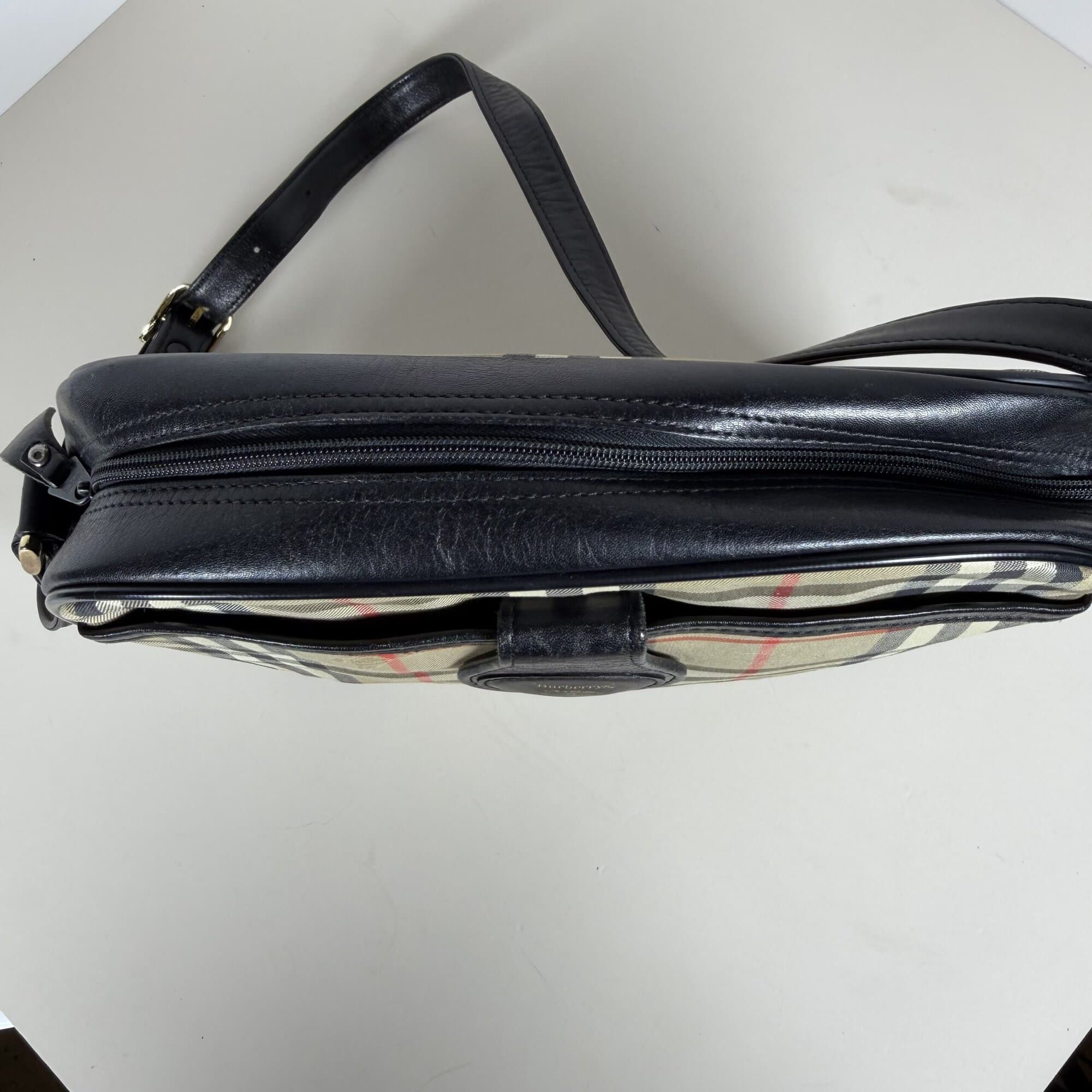 Top view of Burberrys crossbody bag showing black leather panel and zipper closure.