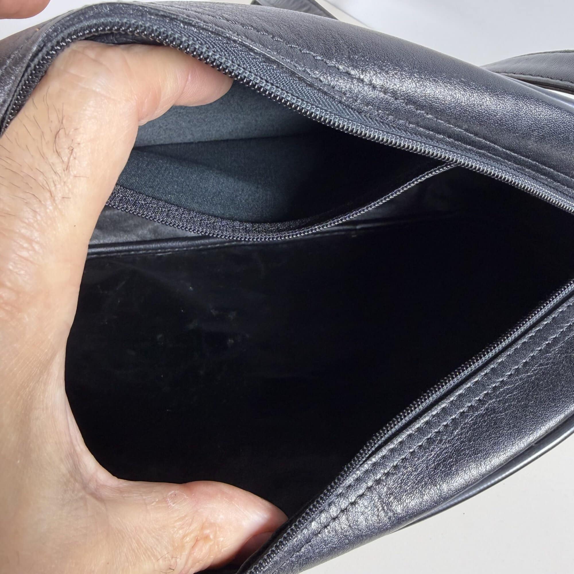 Interior main compartment of Burberrys crossbody bag showing black lining and interior zip pocket.