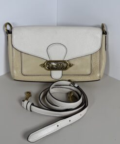 Front view of Coach Jade shoulder bag with detachable white strap coiled in foreground