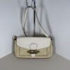 Coach Jade colorblock shoulder bag in white and beige hanging on display stand