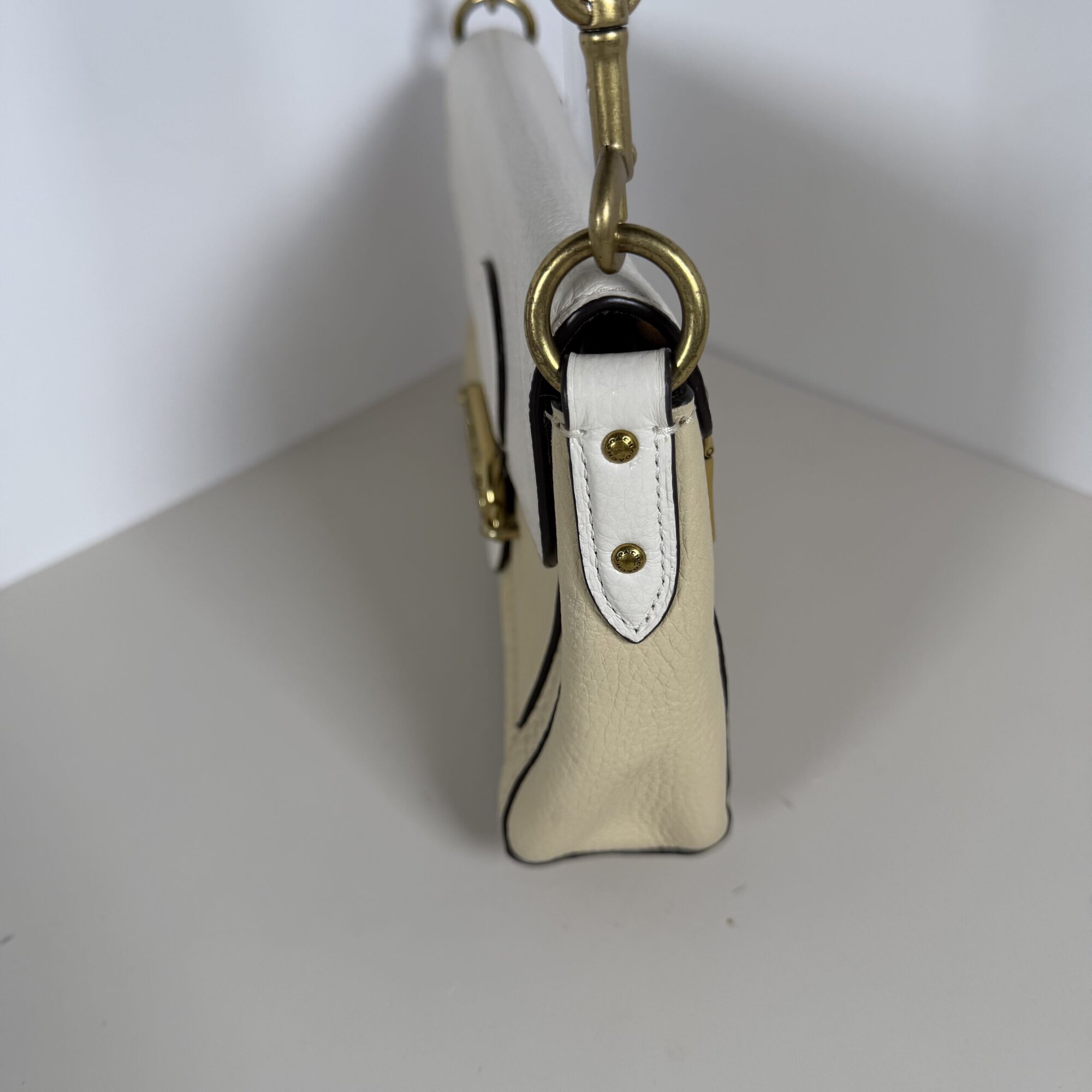 Side profile of Coach Jade bag showing cream leather gusset and gold-tone d-ring hardware