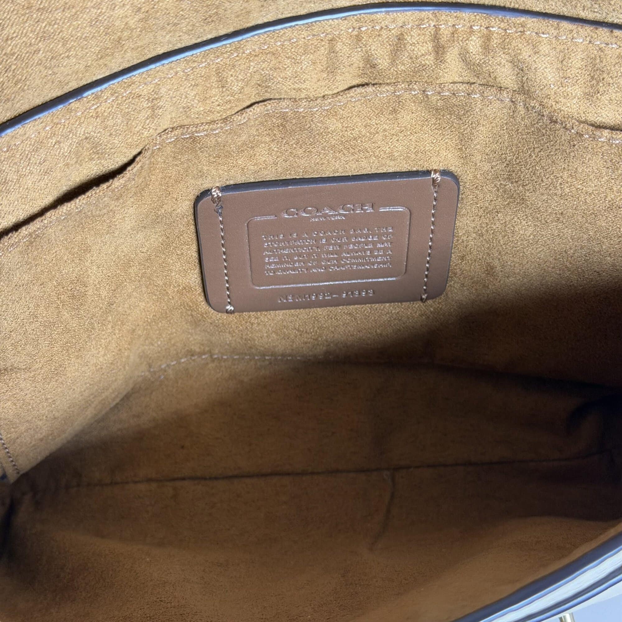 Open interior view of Coach Jade bag showing brown fabric lining and leather creed patch