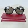 Front view of black Gucci oversized sunglasses resting on a red Gucci case.