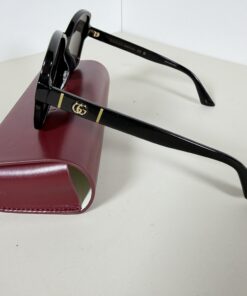 Side view of Gucci sunglasses showing black temple with gold-tone Double G logo.
