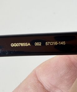 Close-up of inner temple showing gold text GG0765SA 002 57 16-145.