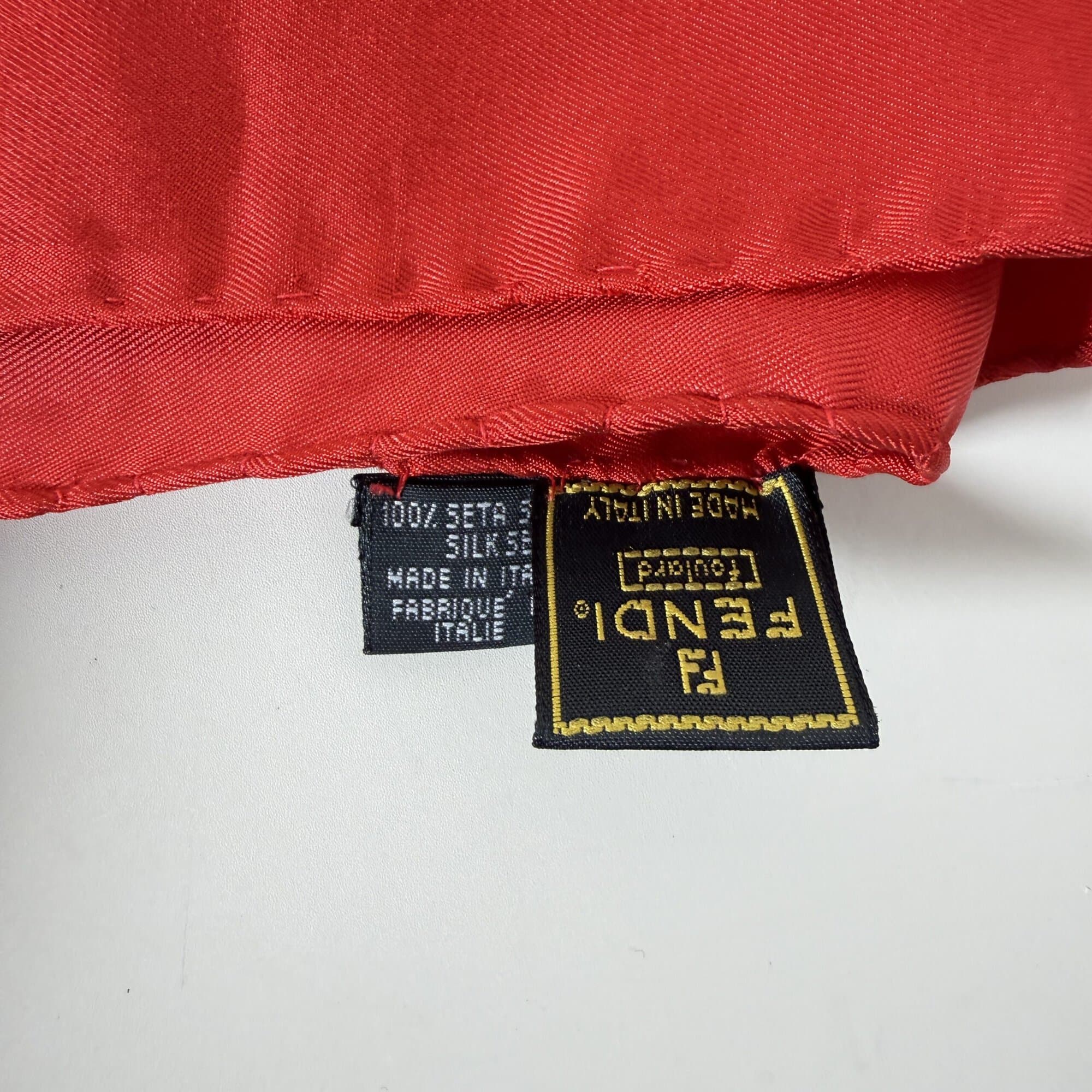 Close-up of Fendi foulard label and 100 percent silk care tag made in Italy along red rolled hem.
