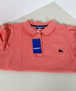 Folded coral Burberry Blue Label polo shirt showing collar, chest logo, and attached tag