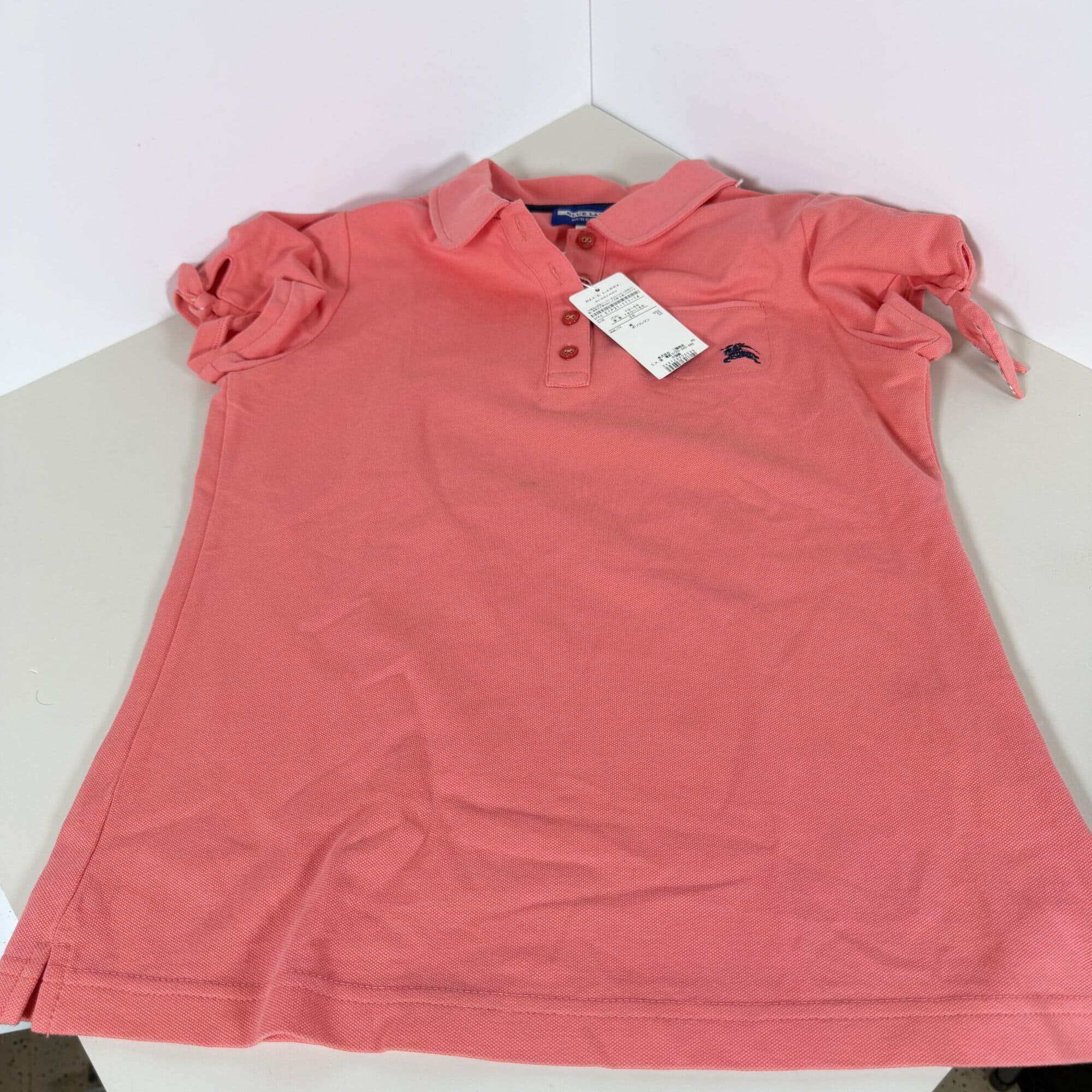 Full front view of coral short-sleeve polo shirt with Peter Pan collar and button placket
